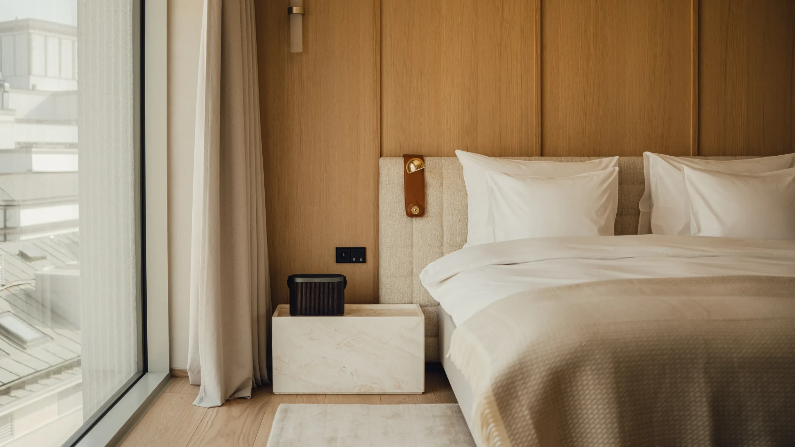 Inside the PURO hotel bedroom, Beosound A5 standing on a night stand next to the bed.