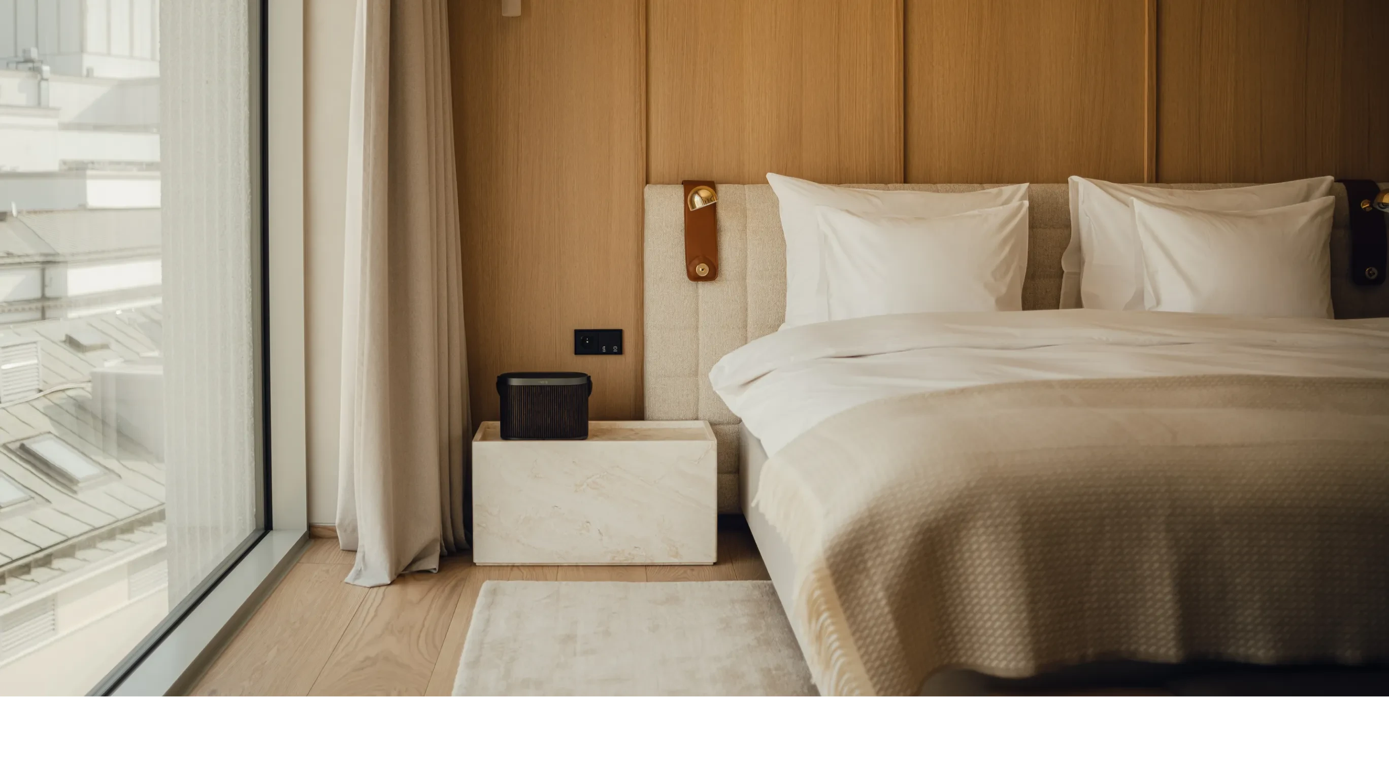 Inside the PURO hotel bedroom, Beosound A5 standing on a night stand next to the bed.