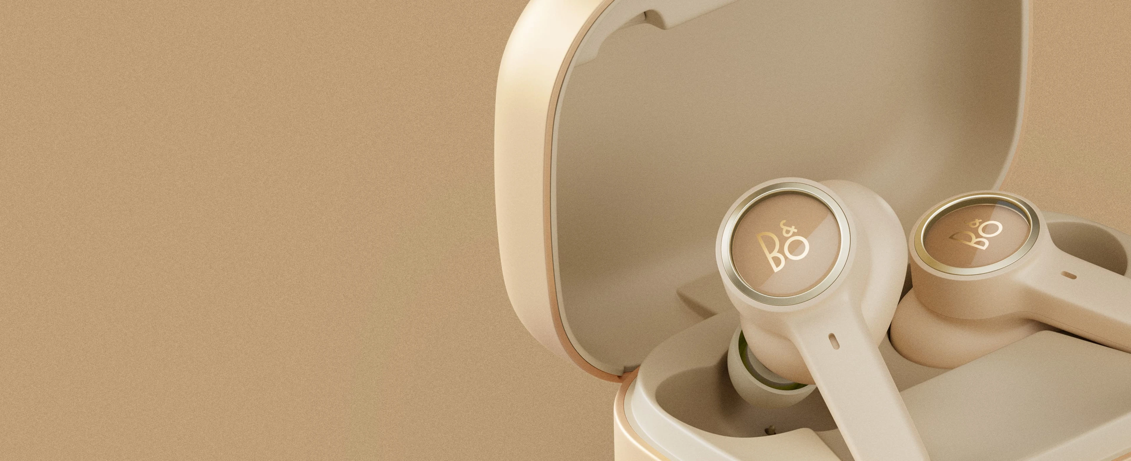 Bang & Olufsen Beoplay EX  Premium wireless earbuds Beoplay EX in gold tone variant laying in charging dongle