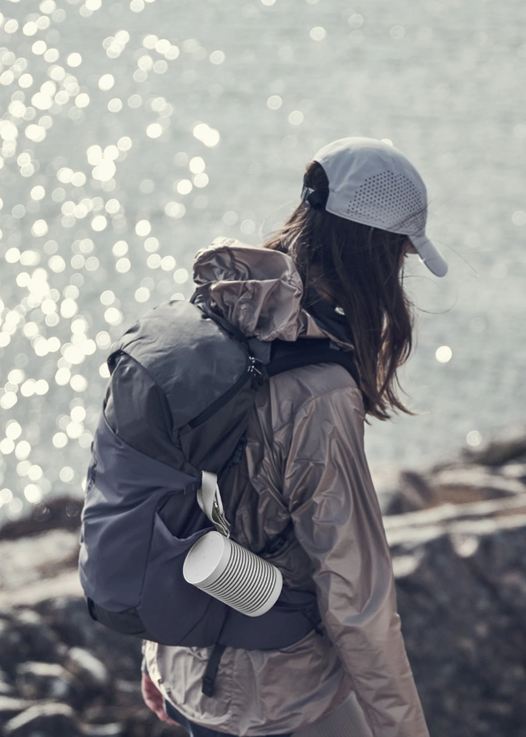 Girl walking on the rock side with Beosound Explore attached to the backpack