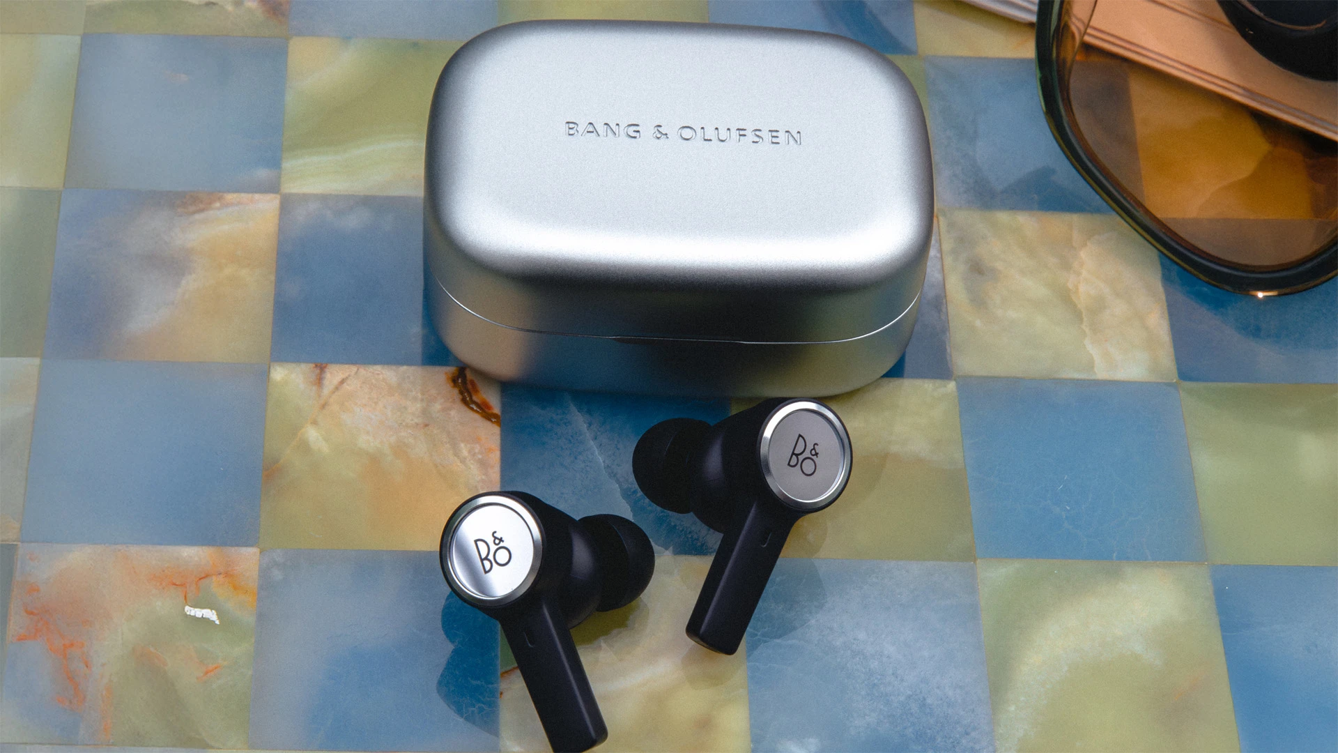 Beoplay Eleven earphones and case on a marble table