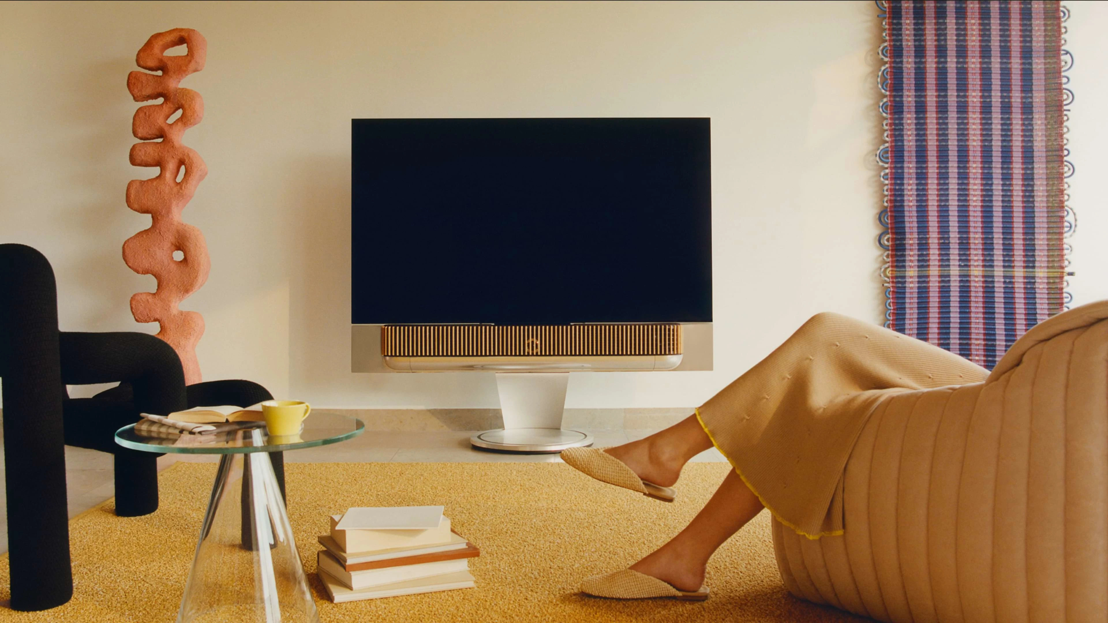 Person sits on chair next to a Beovision Theatre