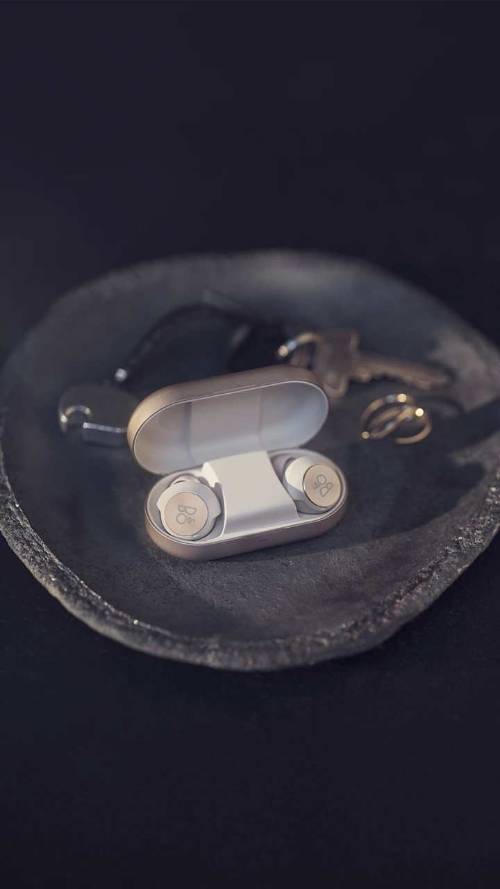 Beoplay EQ earphones and charging case on a decorative tray