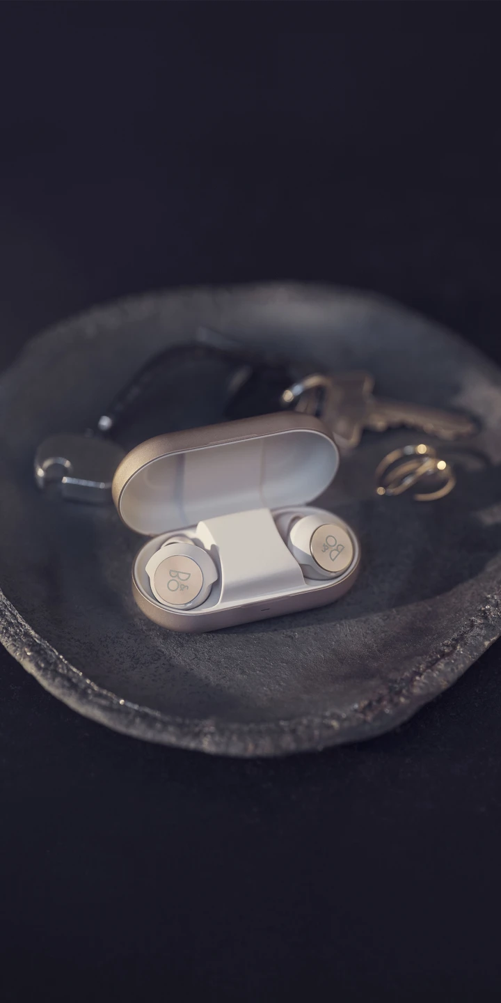 Beoplay EQ earphones and charging case on a decorative tray
