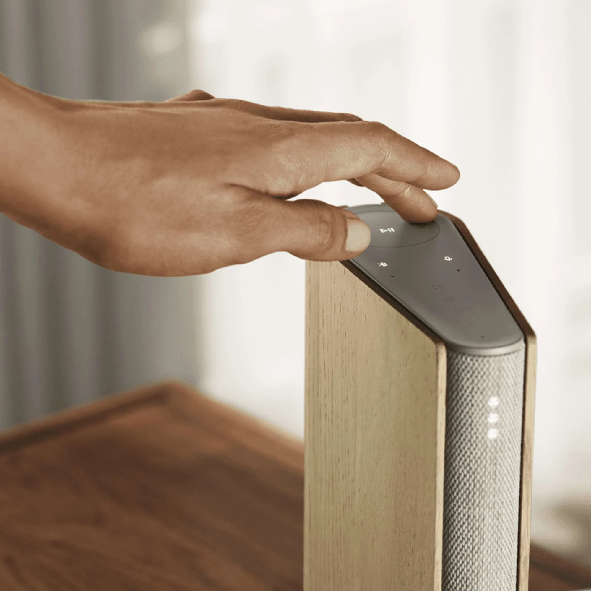 Beosound Emerge with a hand adjusting the settings