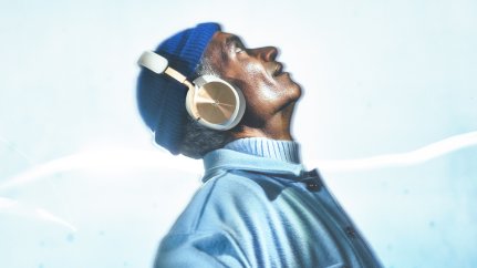 Man waarin Beoplay H95 headphones in brown wearing a navy cap