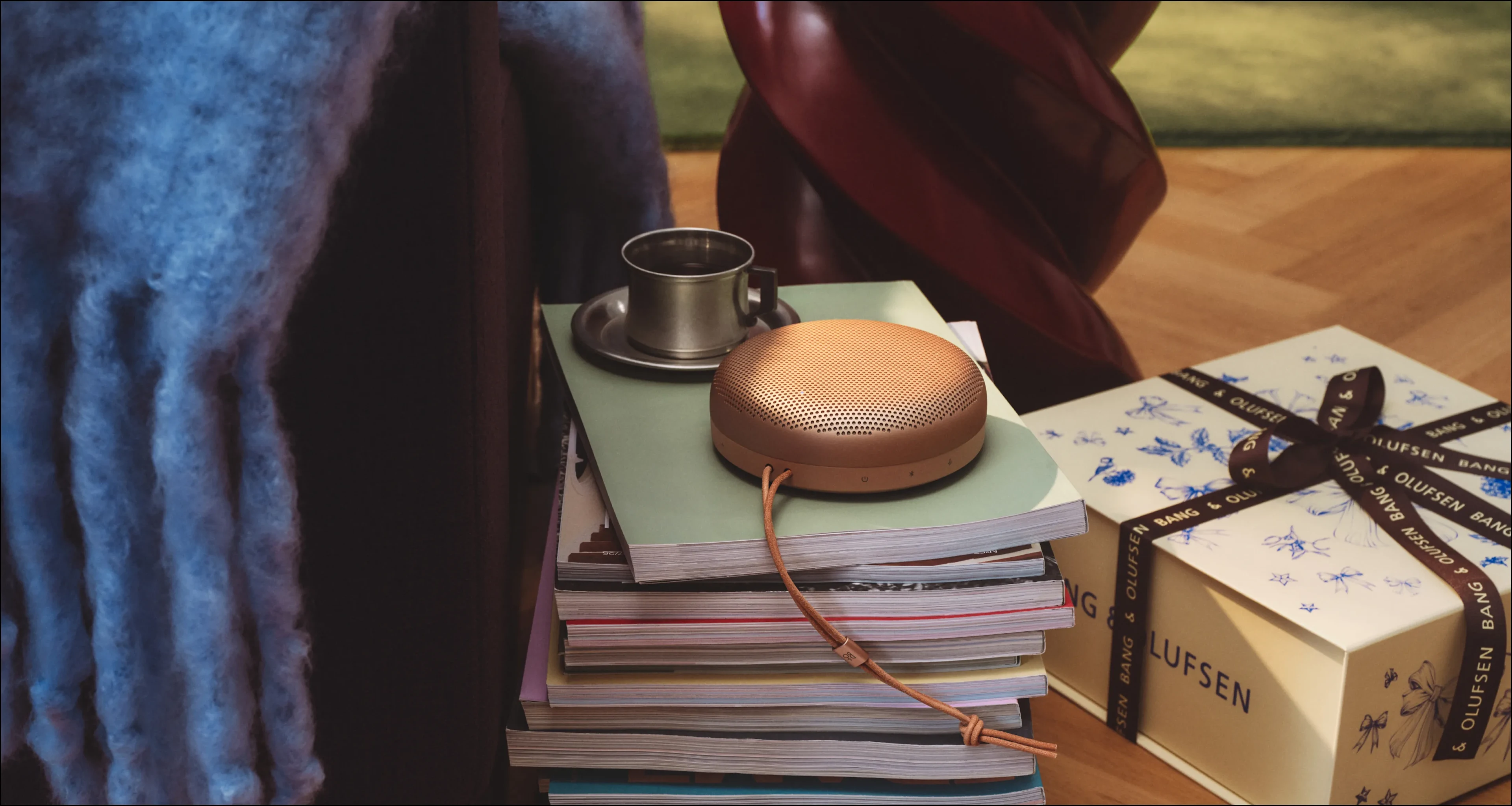 書堆上擺放著 Beosound A1 第 3 代 Honey Tone，Bang & Olufsen 禮盒的一旁有一杯茶
