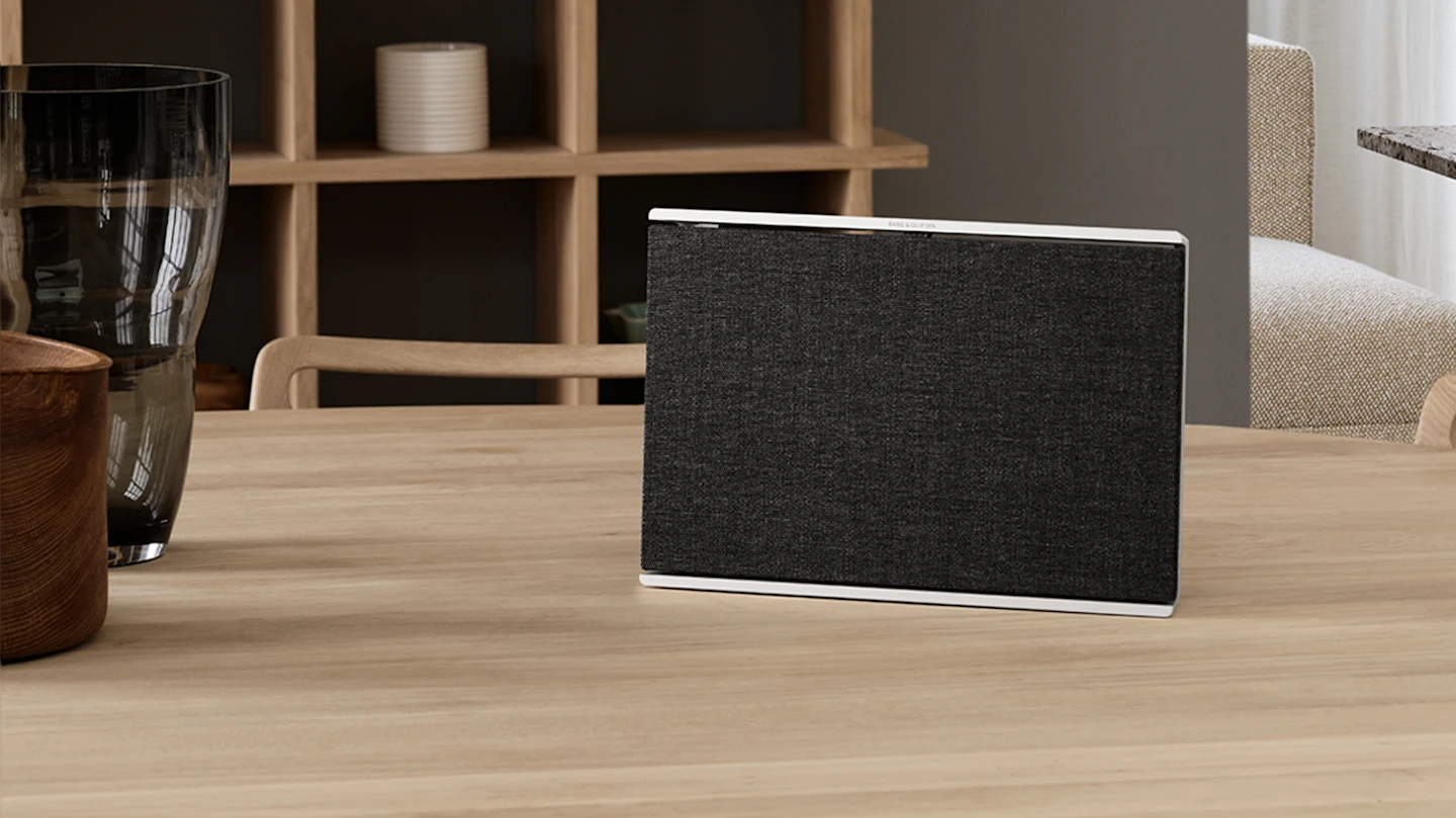  Beosound Level Natural - Dark Grey placed upright on a wooden table in a living room