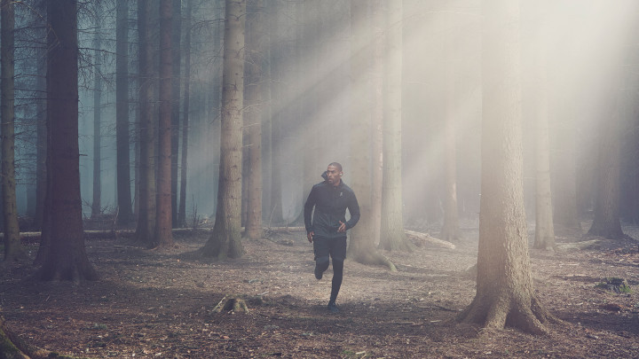 A man wearing Beoplay E8 sport while running in the forest