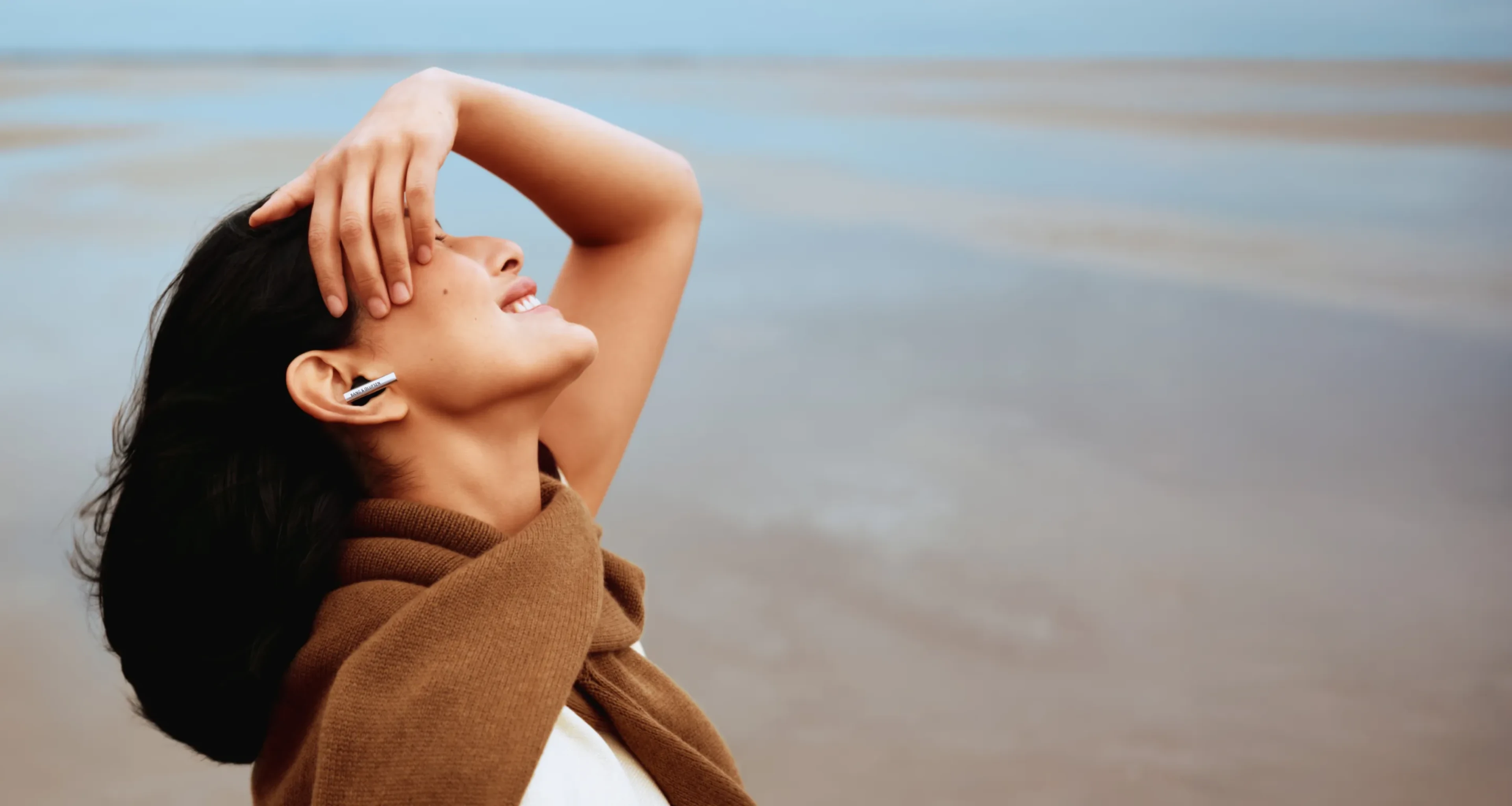 Side face of a woman smiling who's wearing Beo Grace and feeling the music