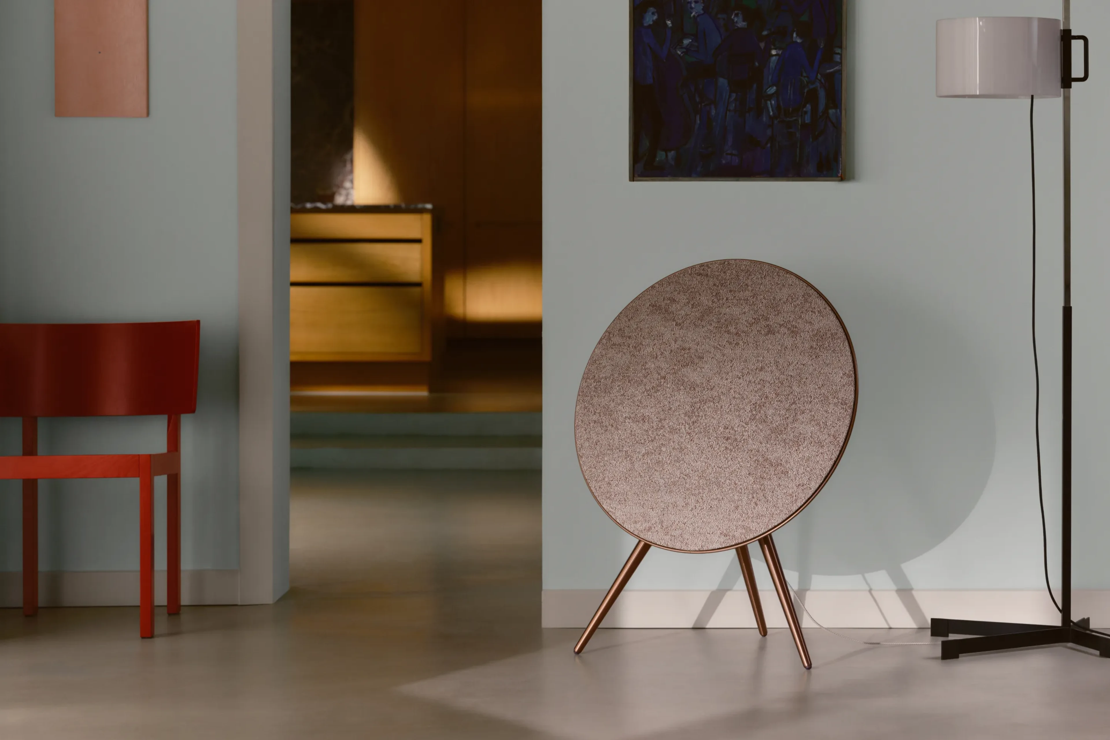 Beosound A9 in color variant Sienna Brown in a room with a lamp.
