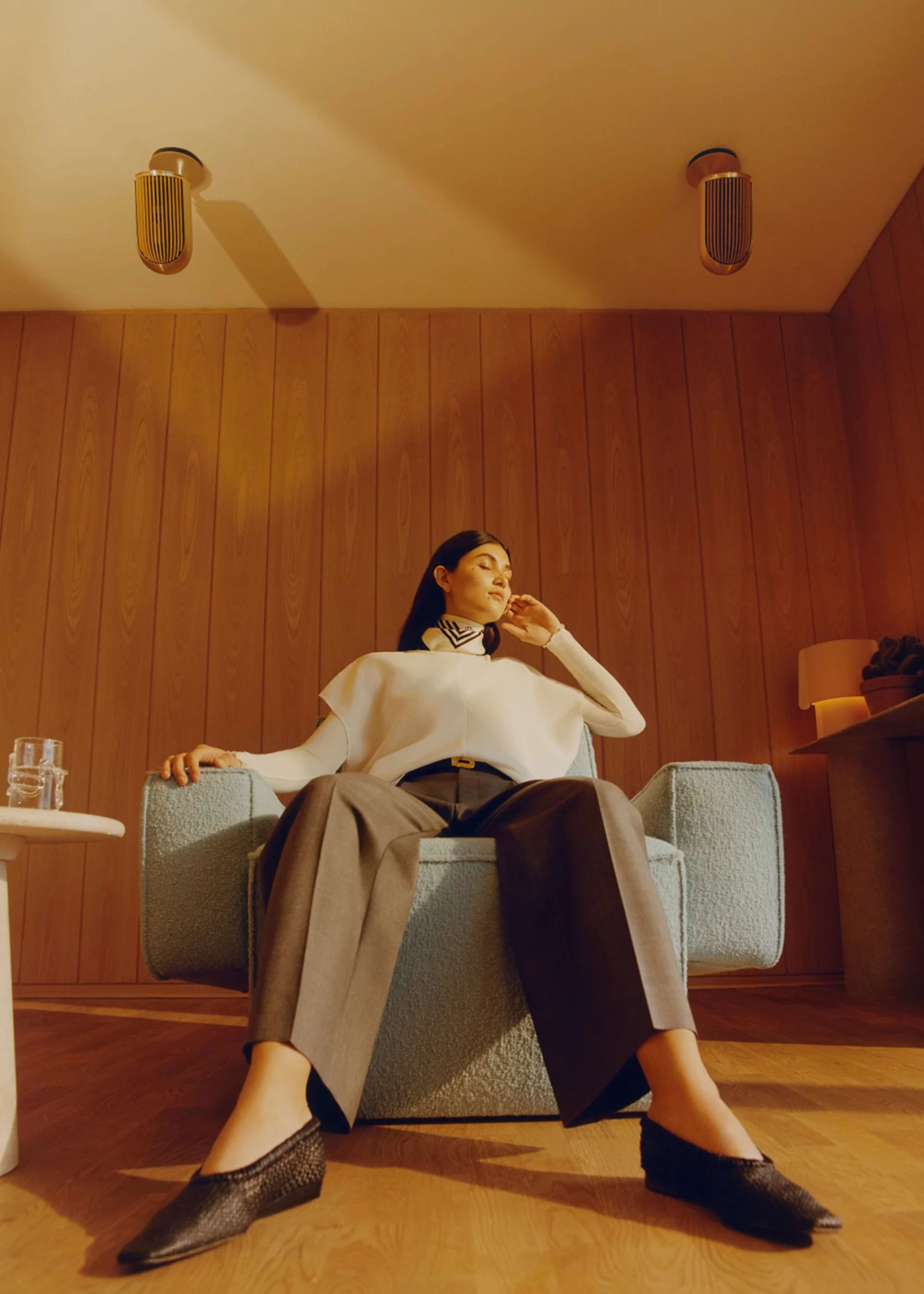 Person sitting in chair with Beolab 8 on the wall in the background