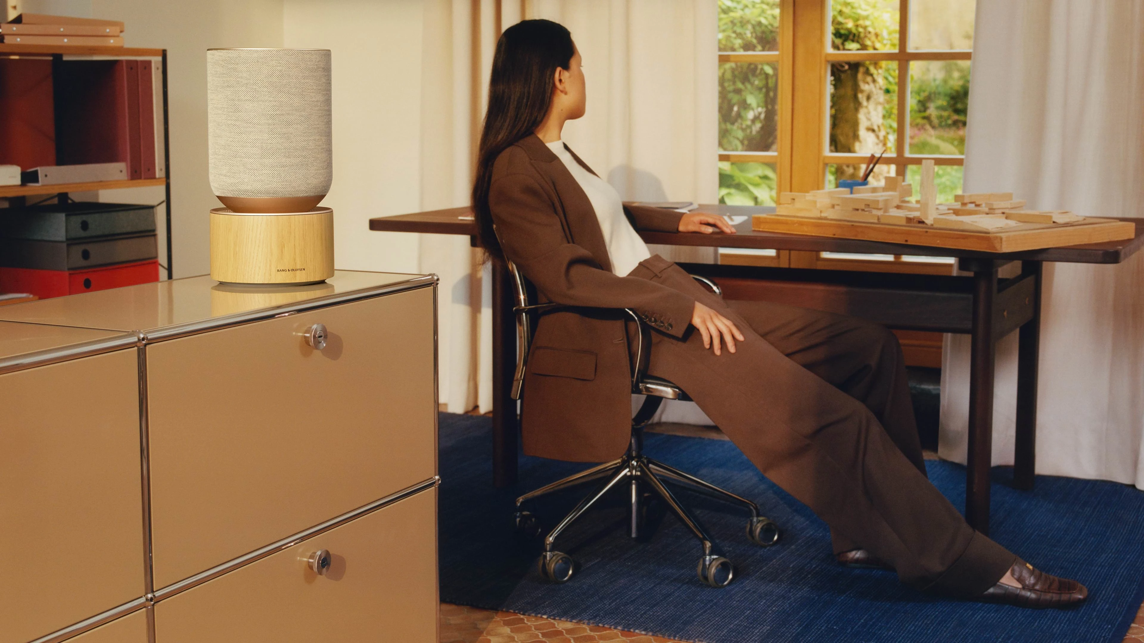 Person leaning back on chair while the Beosound Balance is displayed on a counter