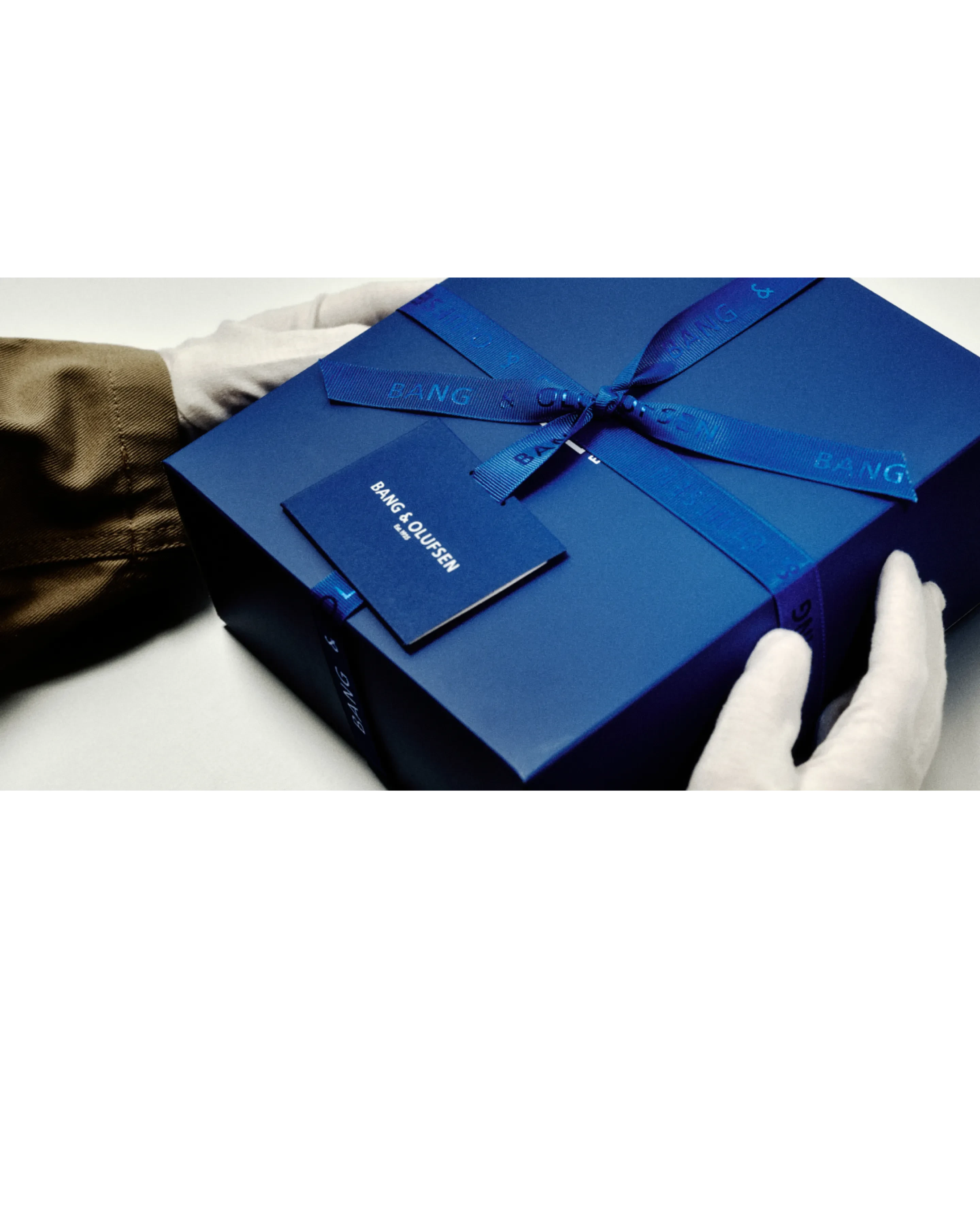 Un par de manos con guantes blancos sujetan la caja de envoltorio de regalo Future Blue
