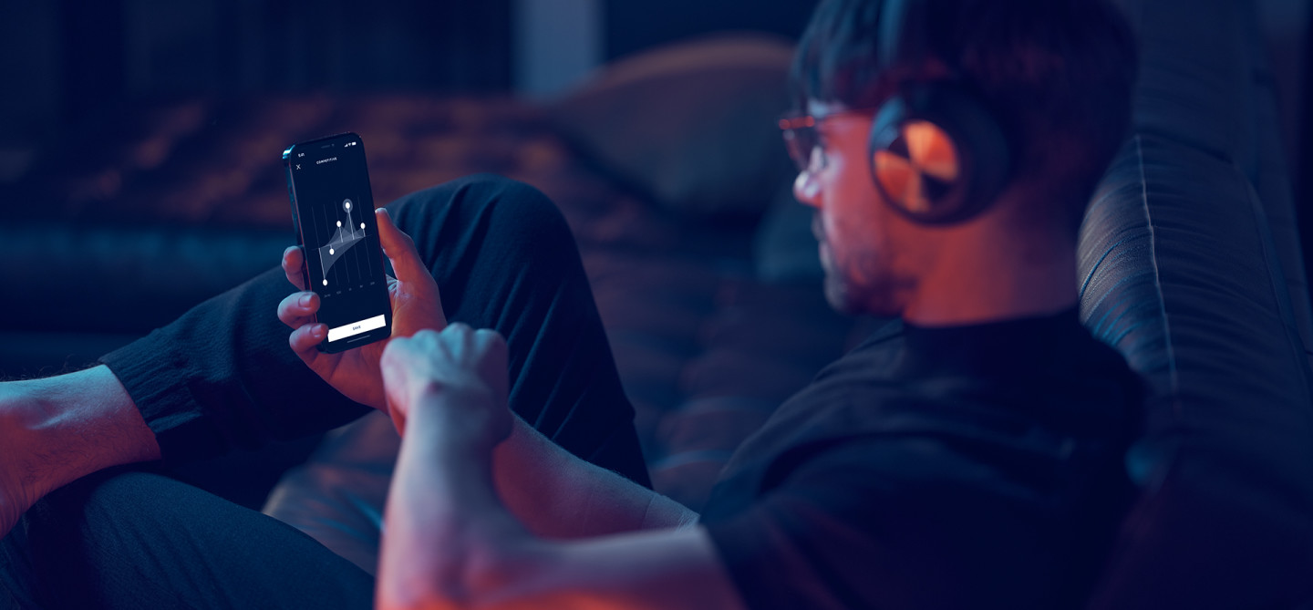 Man playing a game on mobile phone wearing Beoplay Portal