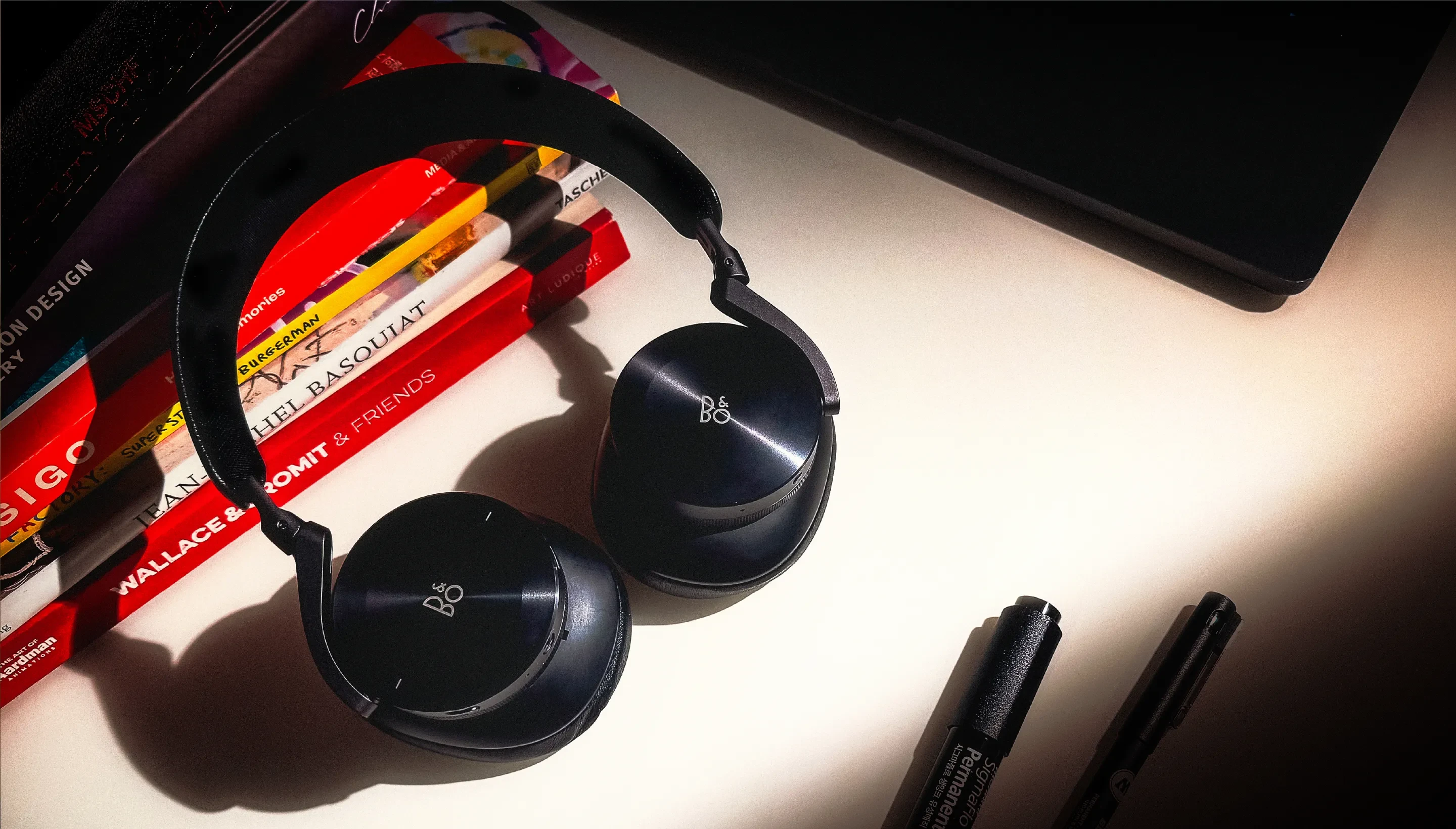 책 더미 옆 테이블 위에 놓인 Beoplay H95 블랙 색상 모델