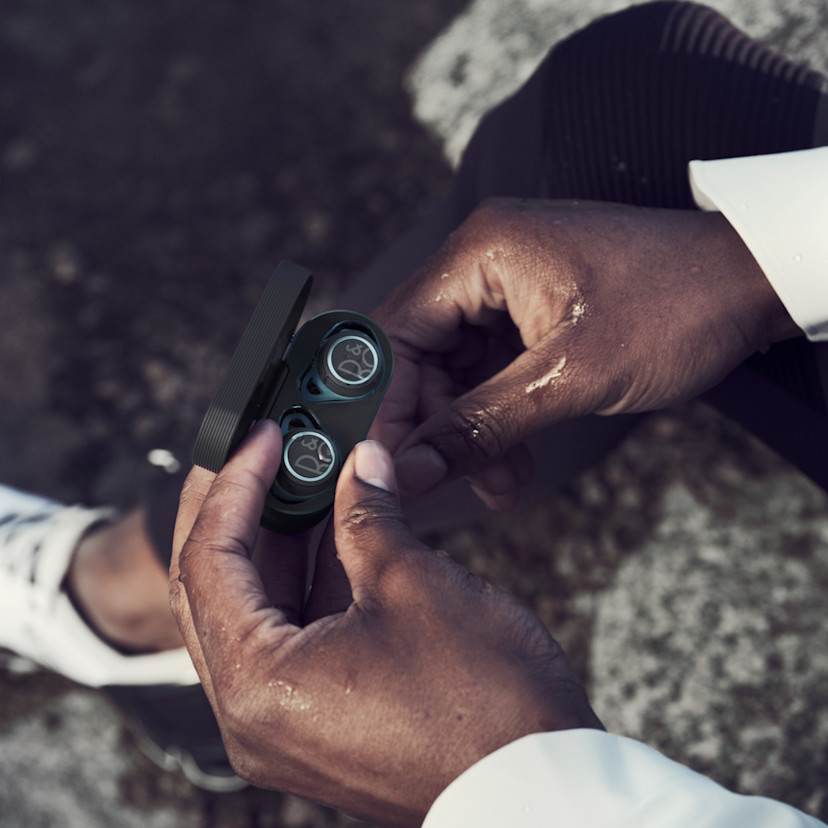 Beoplay E8 sport earphones with a splash of water in the hands of a runner