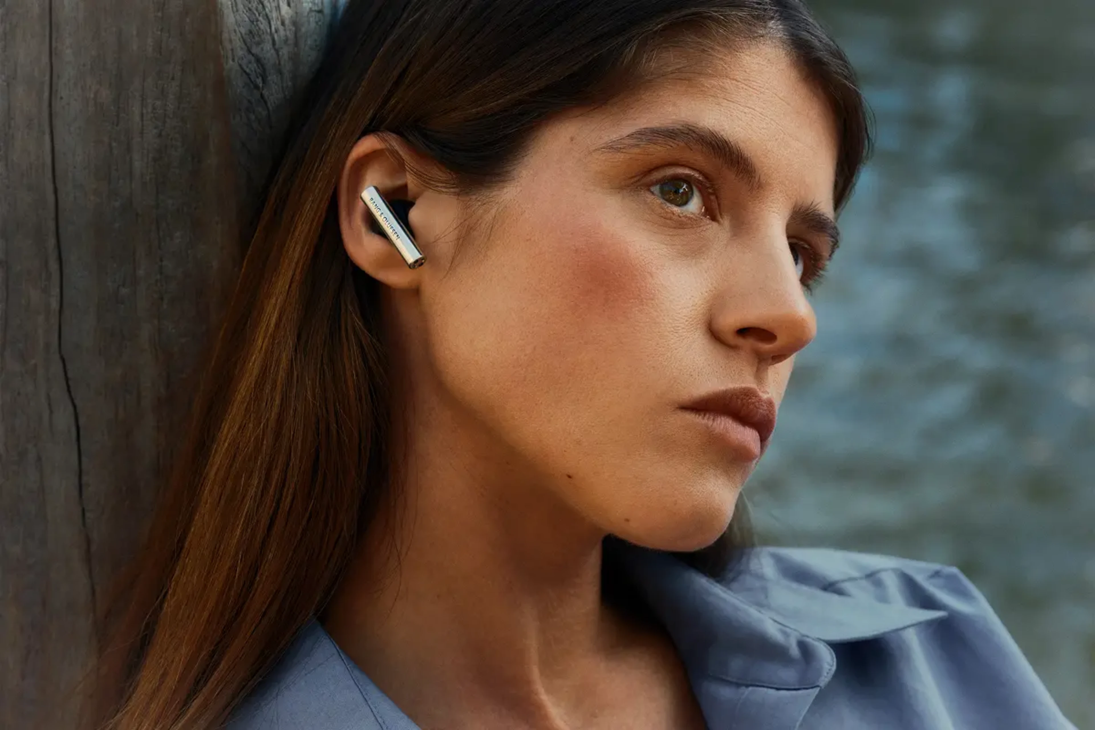 A woman wearing Beo Grace headphones while relaxing by the water