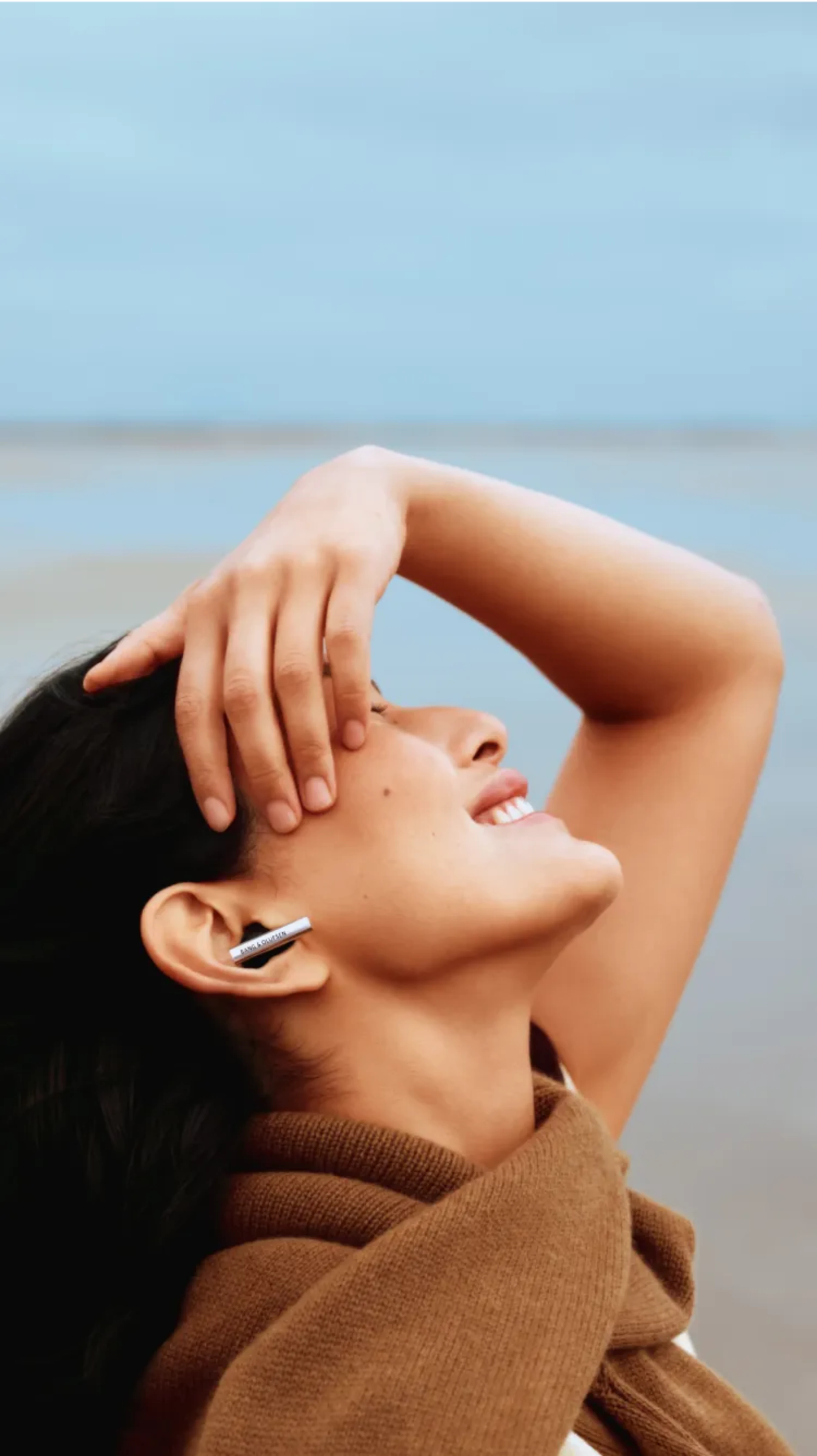 一位女士的側臉,她面帶微笑並佩戴 Beo Grace,盡情感受美妙樂聲