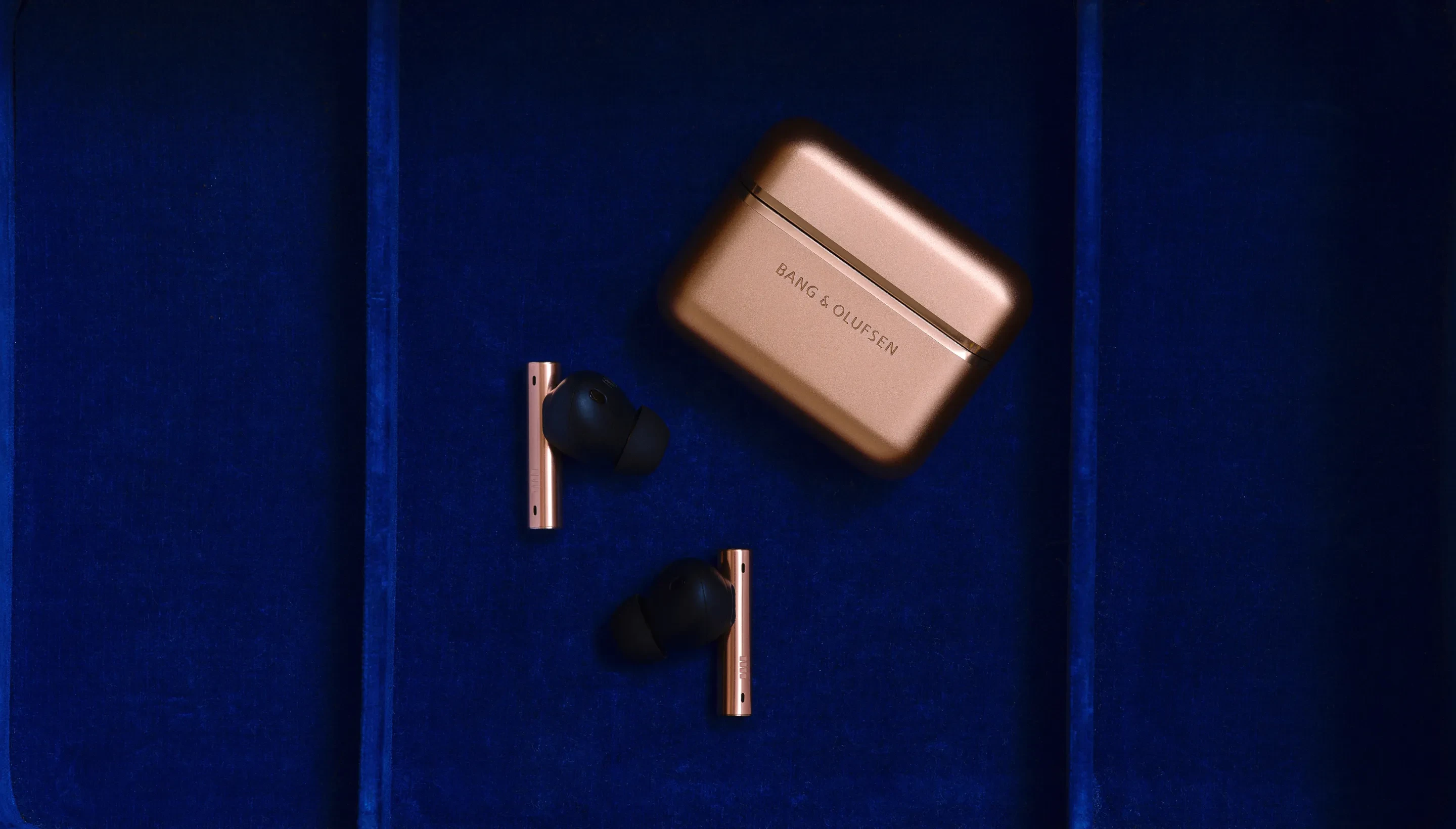 Image of Beo grace in Honey Tone variant. The ear phones are out of the case on a dark blue background