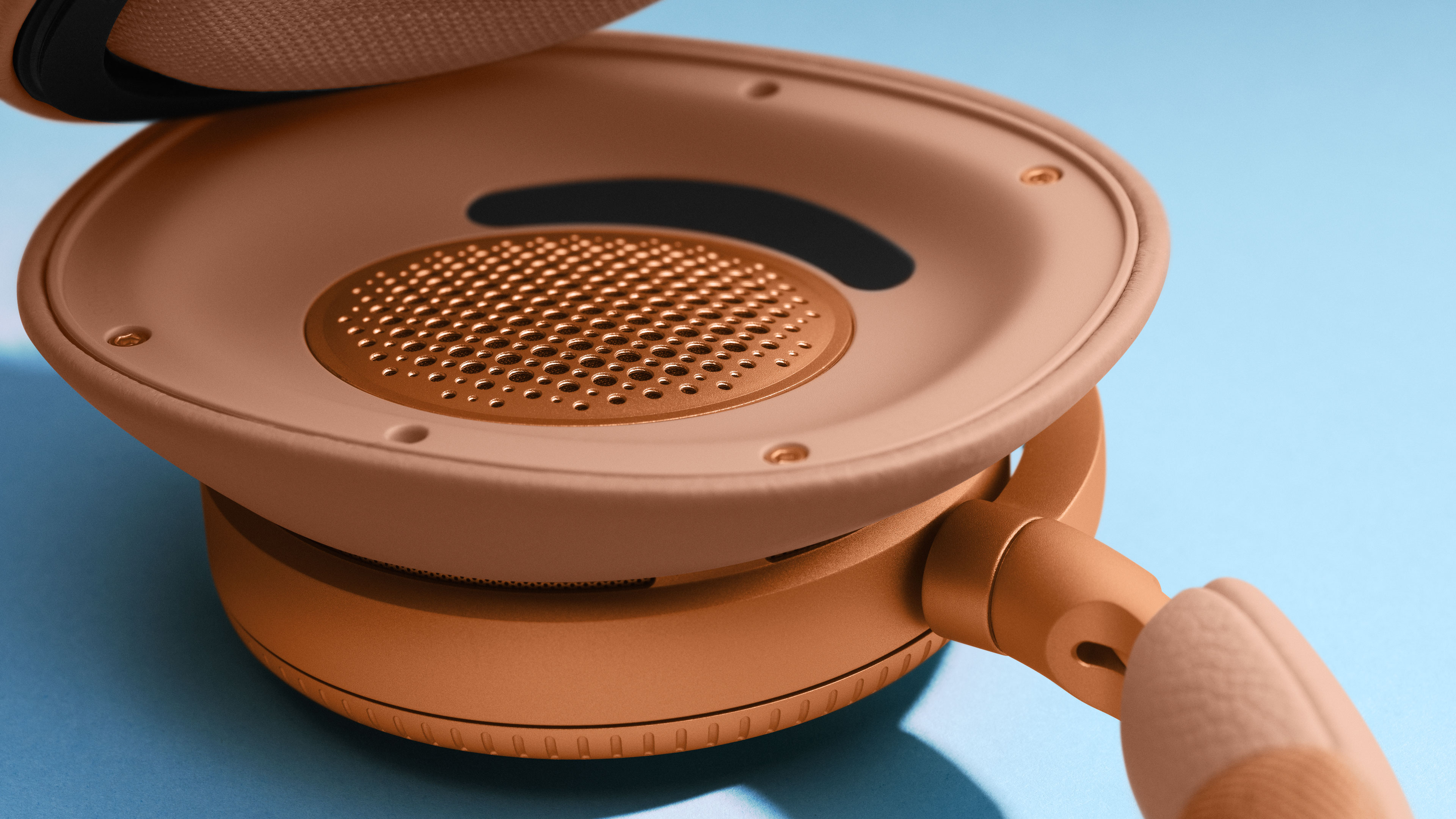 Detail shot of Beoplay H100 headphones under ear cushion in the colour Sunset Apricot