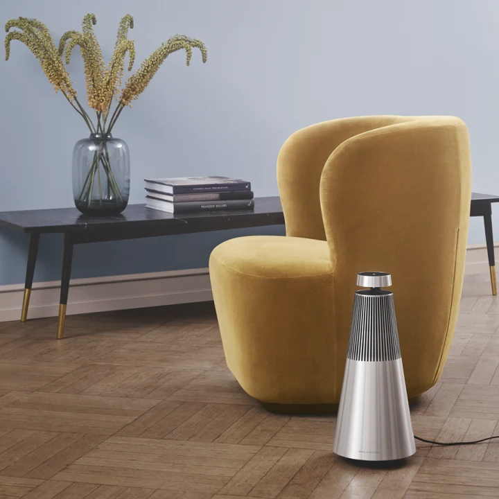 Beosound 2 in grey natural aluminium placed next to a yellow chair