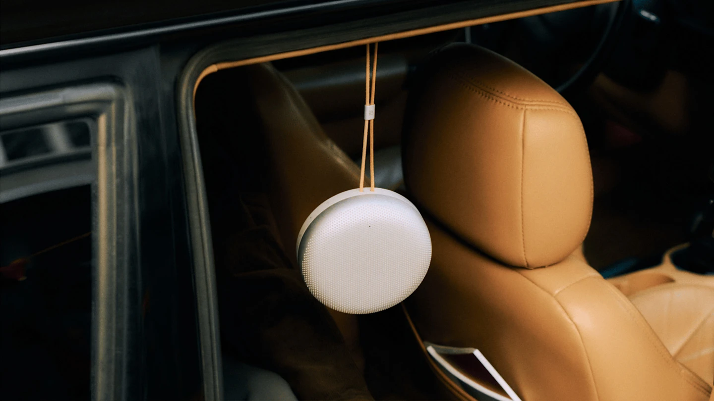 Beosound A1 3rd Gen hanging from the door of a car