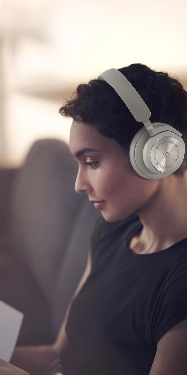 A woman wearing Beoplay HX Sand while working