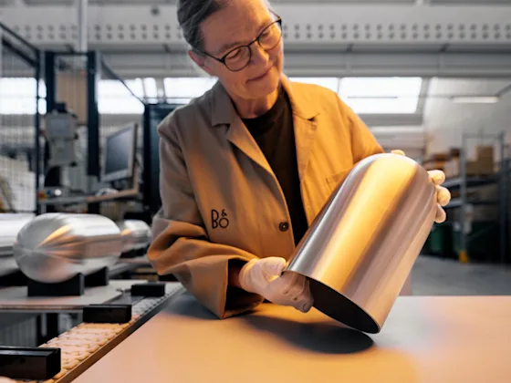 Un lucrător Bang & Olufsen verifică o husă de aluminiu anodizat auriu