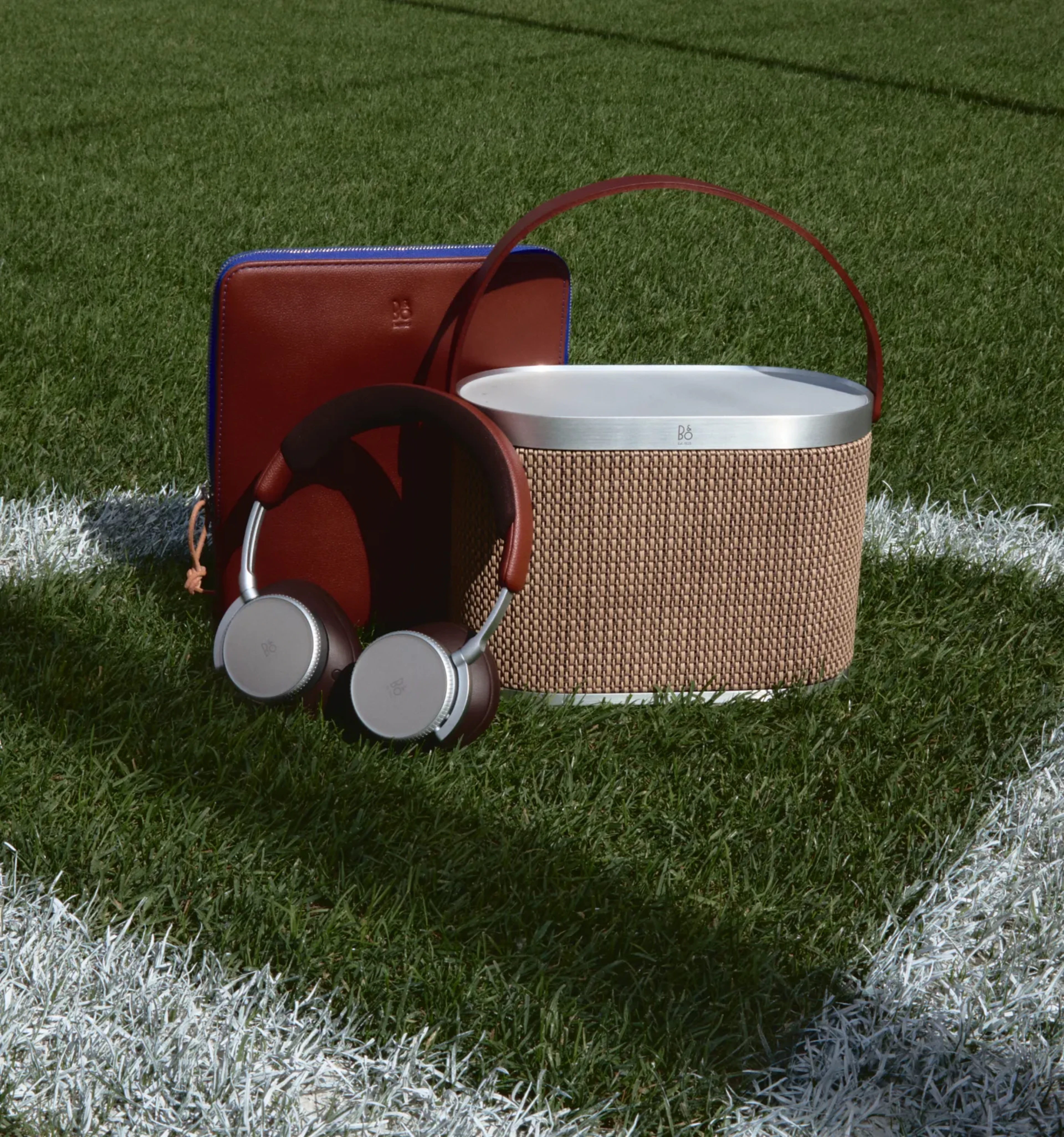 Beoplay H100 Centennial variant with its pouch case and Beosound A5 Centennial variant on the football field