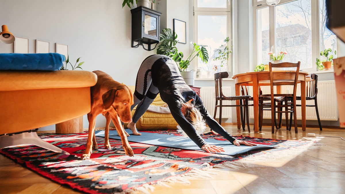 Woman doing yoga with her dog next to her