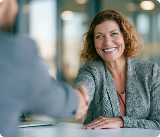 Tax professional shaking hands with a client across a desk