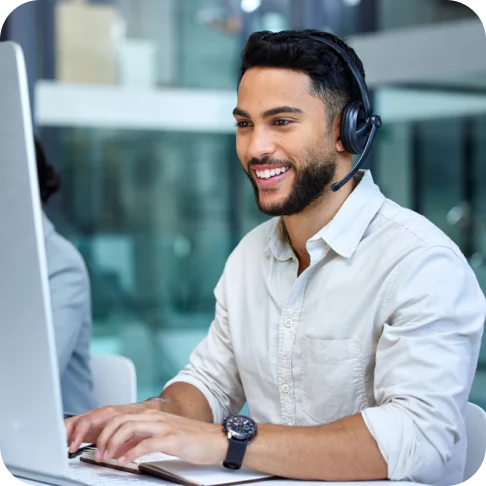 Man working at a computer, wearing a headset microphone. 