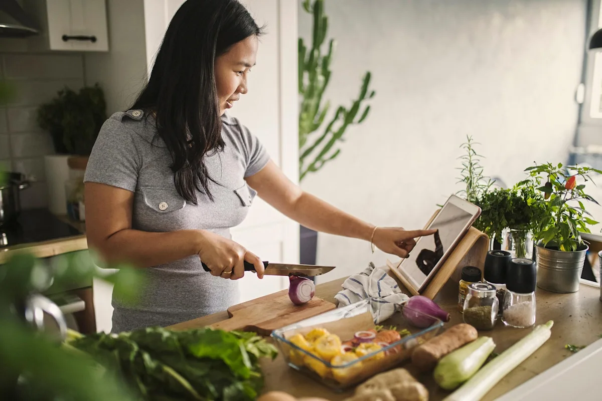 Woman in kitchen cooking with tablet
