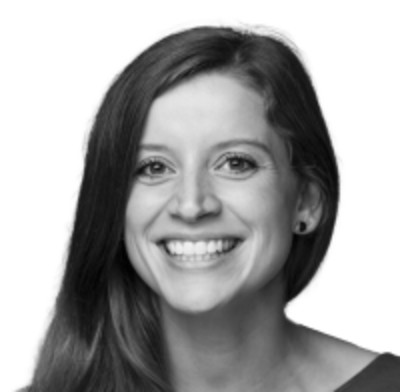 Black and white portrait of a smiling woman with shoulder-length hair, bright eyes, and a cheerful expression.