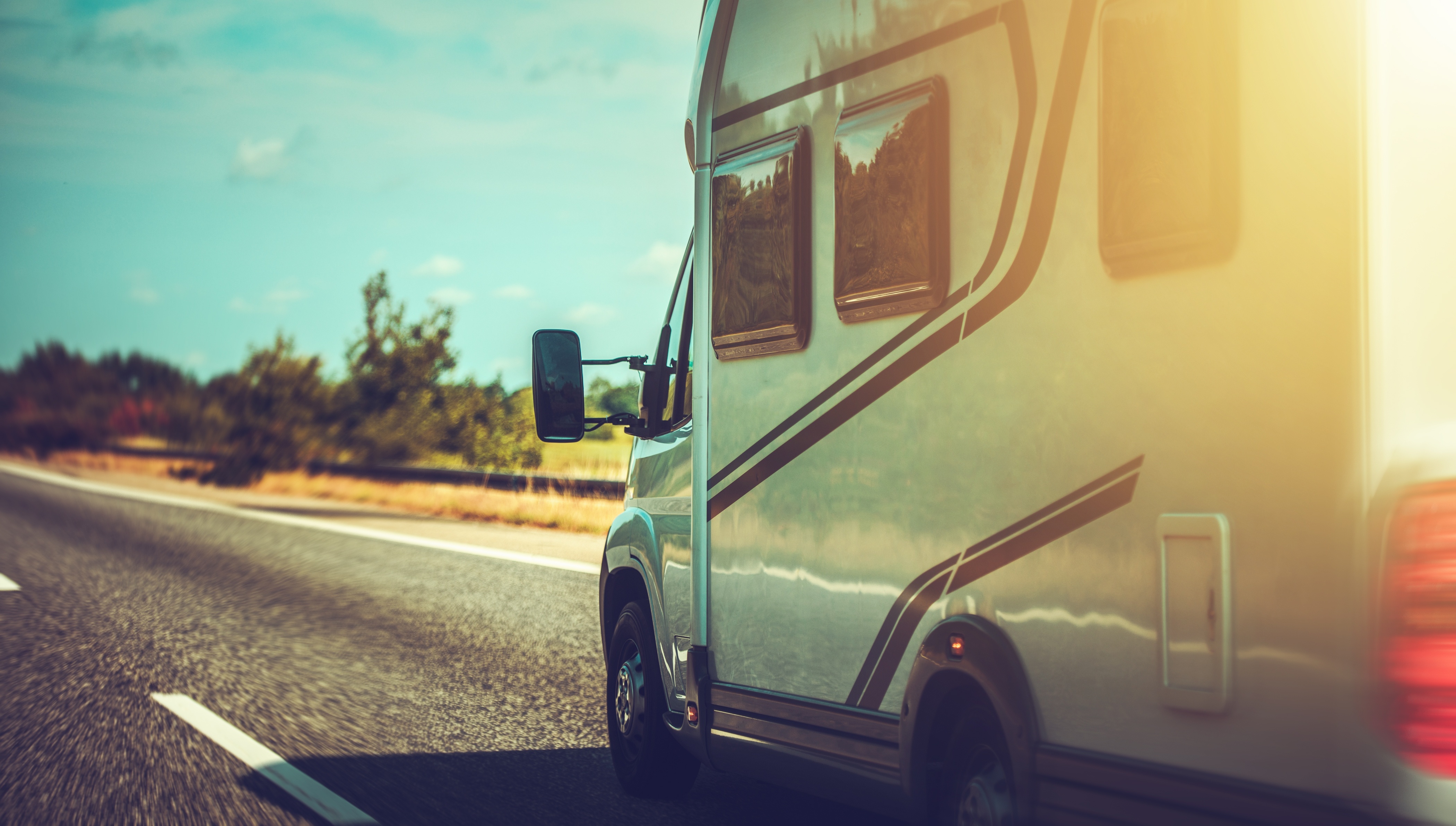 Camping-car sur la route avec un ciel bleu.