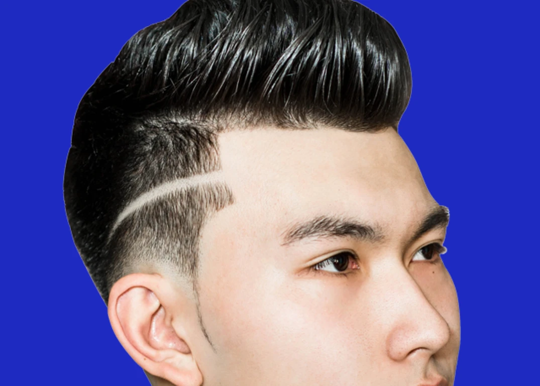 A man with light skin and a pompadour fade haircut looks to the right in front of a blue background.