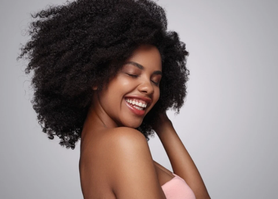 african american woman smiling with her eyes closed as her hand runs through her 4a type curly hair