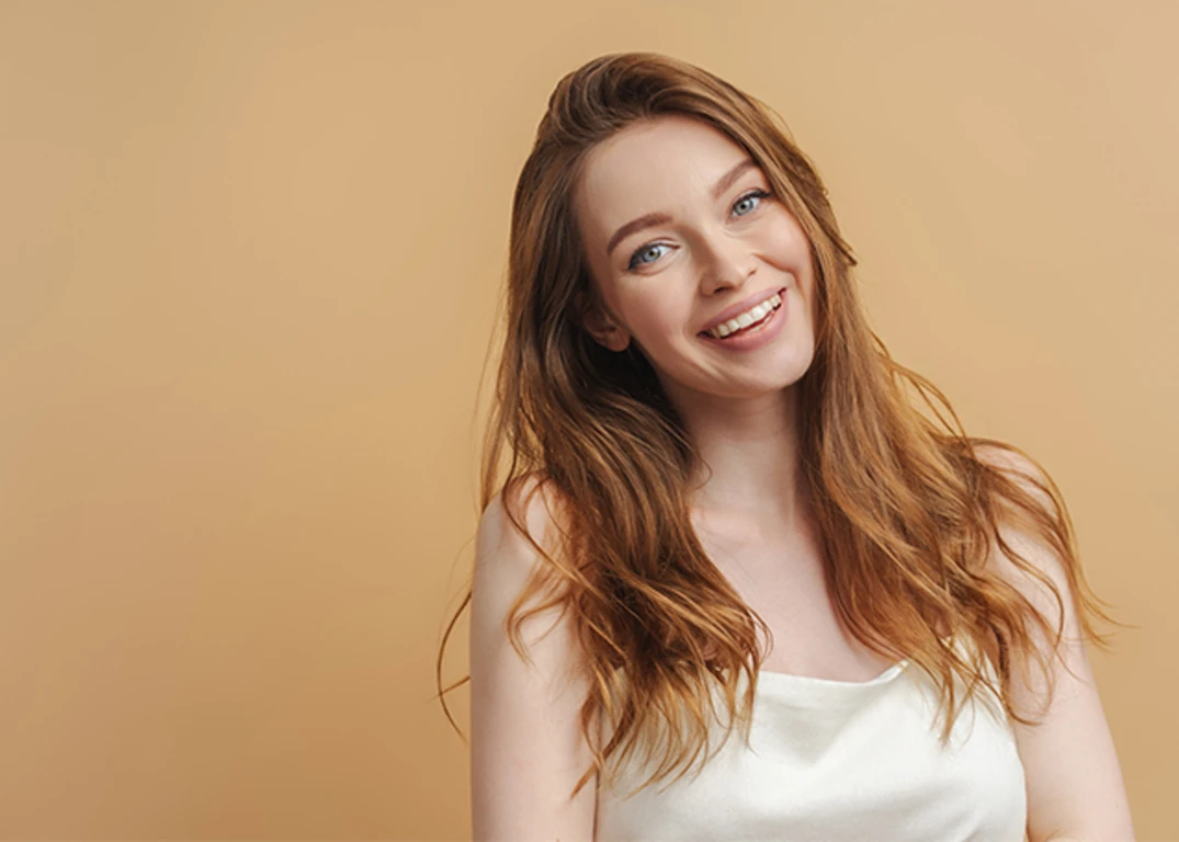 Fair skinned woman with medium length ginger hair smiling wearing a white top