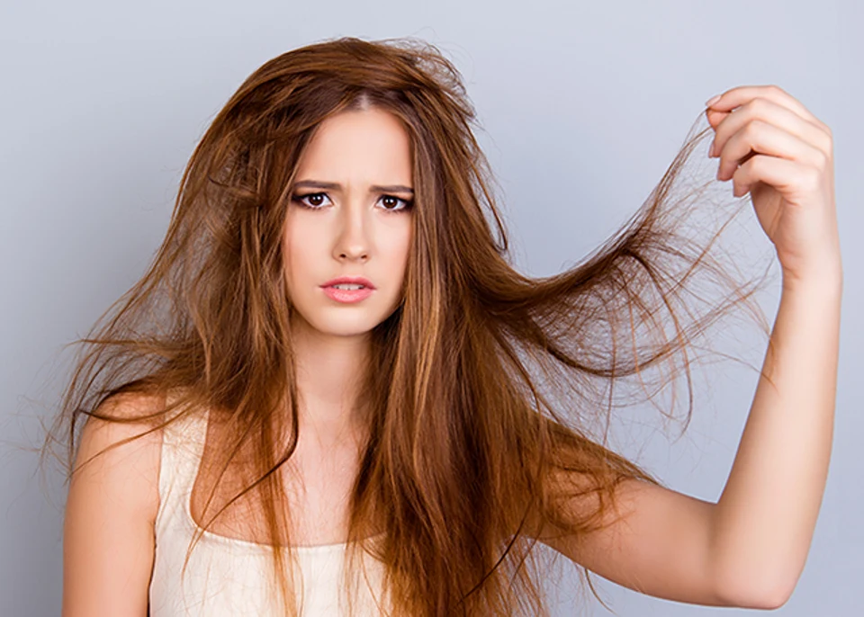 Close up portrait of frustrated young girl with messed hair on pure background, wearing white casual singlet, holding her hair