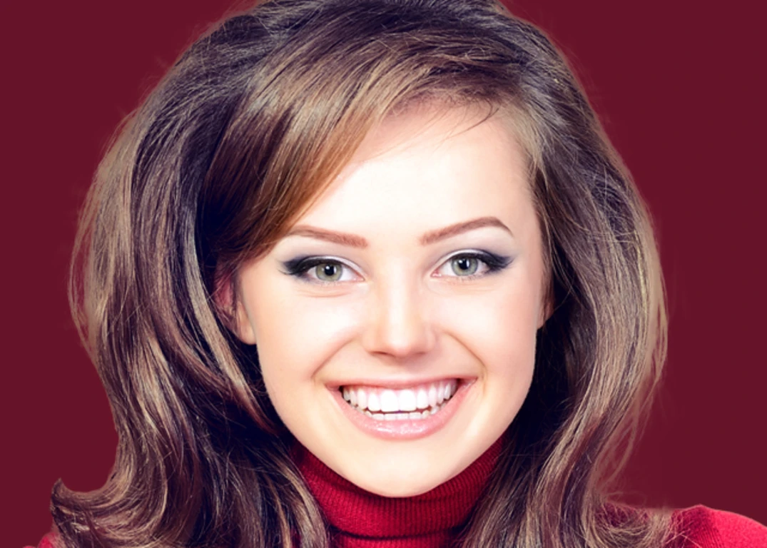 fair skinned woman with a brown, medium length 70’s hairstyle smiles facing forward.