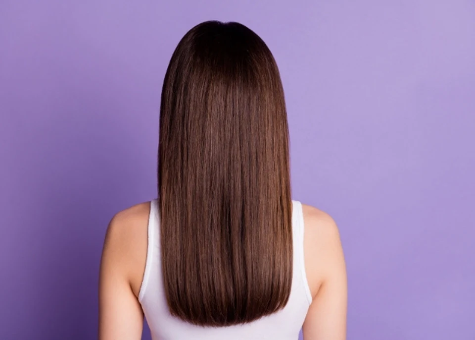 woman with brown straight 1b hair standing with back towards us on a purple background