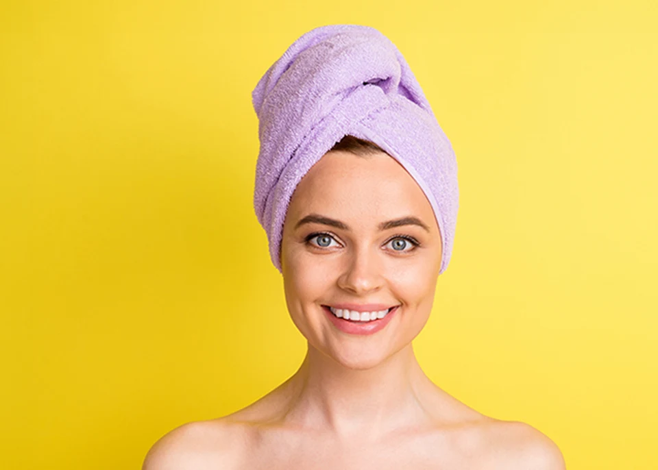 Close-up portrait of lovely cheerful girl wearing towel on head after a fresh shower, isolated over bright yellow color background