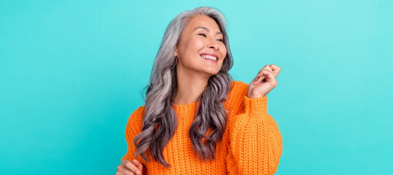 Woman with wavy 2c hair smiling while showing peace sign gesture with hands