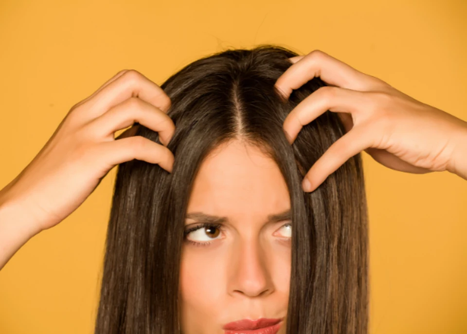 Brown haired woman feeling her oily scalp with her fingers