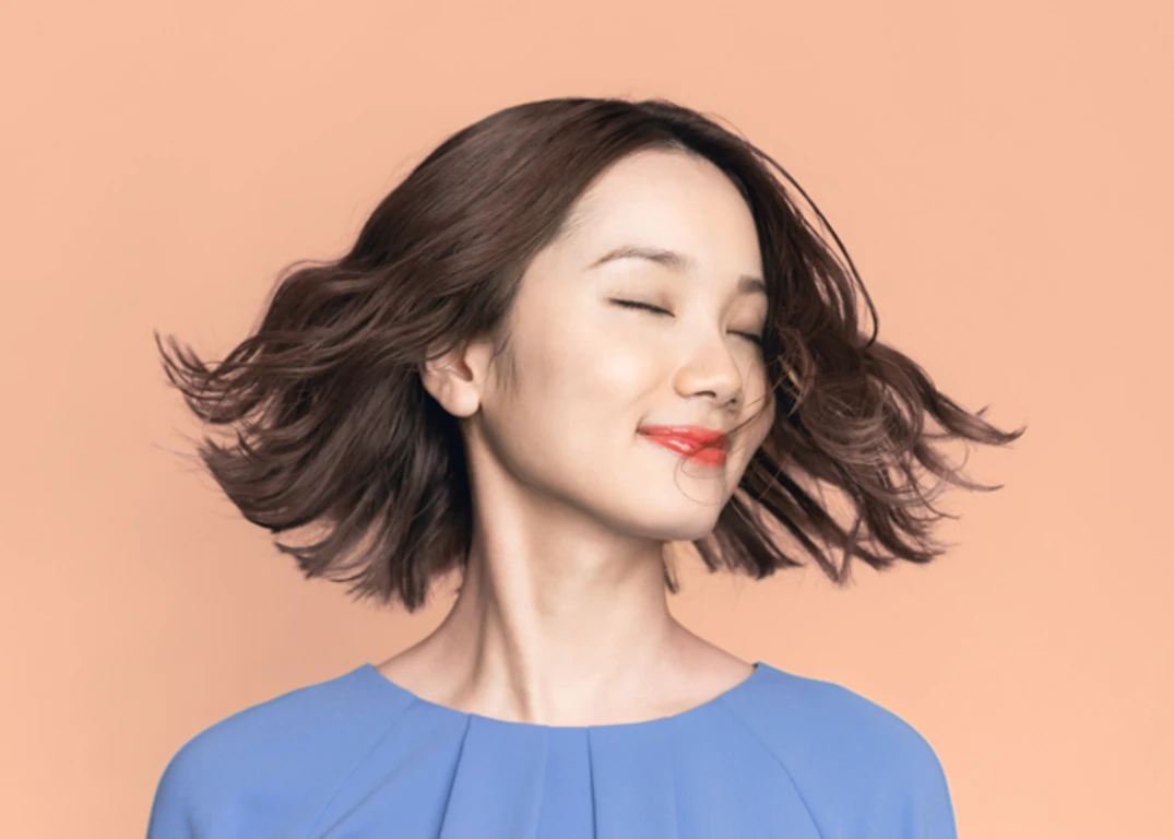 Asian woman with short hair smiling with eyes closed