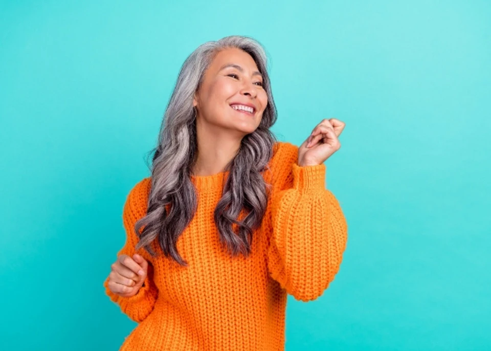 Woman with wavy 2c hair smiling while showing peace sign gesture with hands