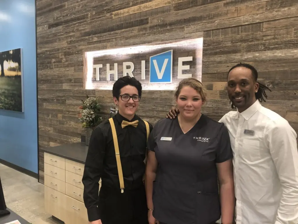 THRIVE Meet and Greet Staff in front of THRIVE office sign