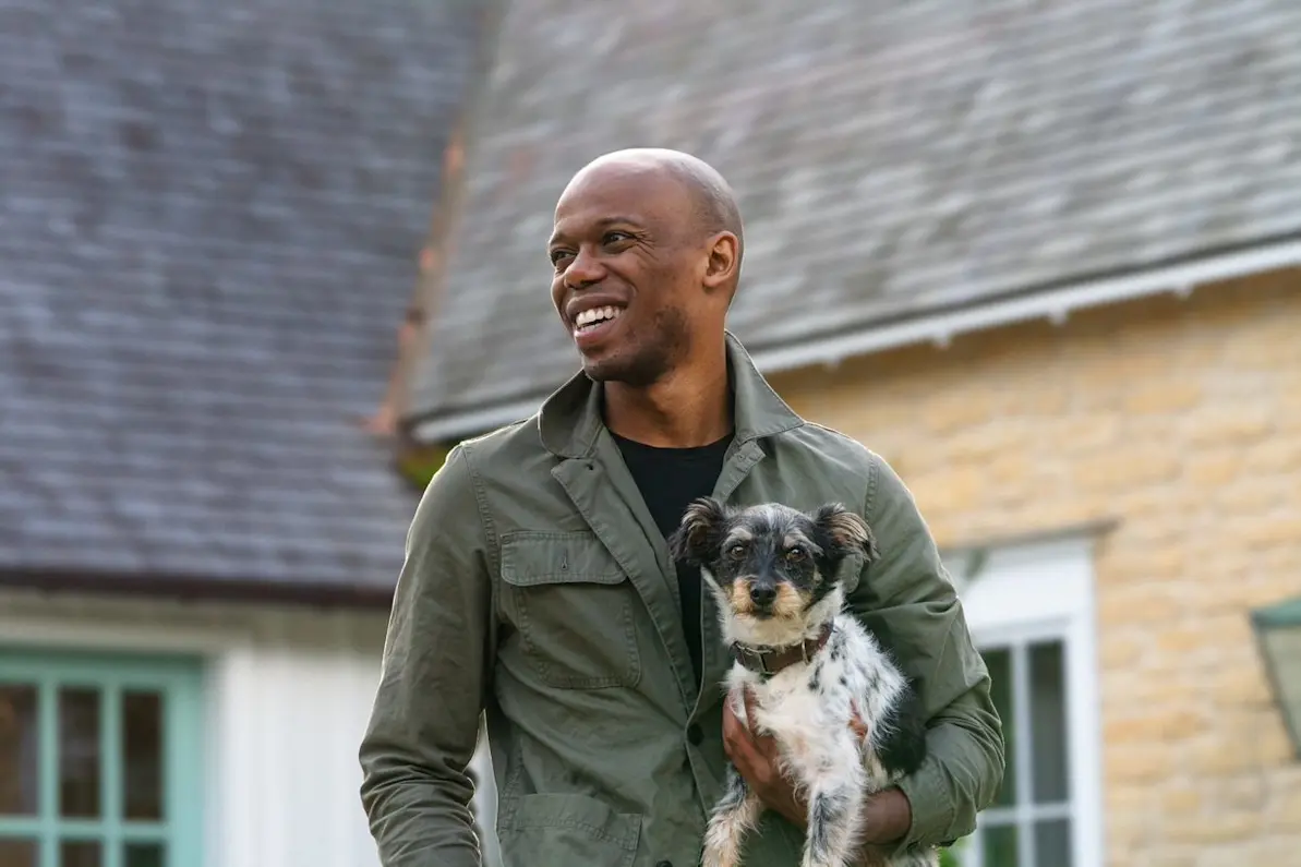 Furry dog staring at camera while man looks away in driveway