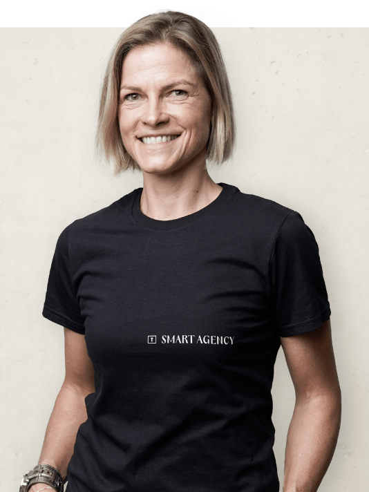 Porträtfoto einer Mitarbeiterin von Smart Agency, lächelnd mit einem Smart Agency T-Shirt vor einem neutralen Hintergrund.